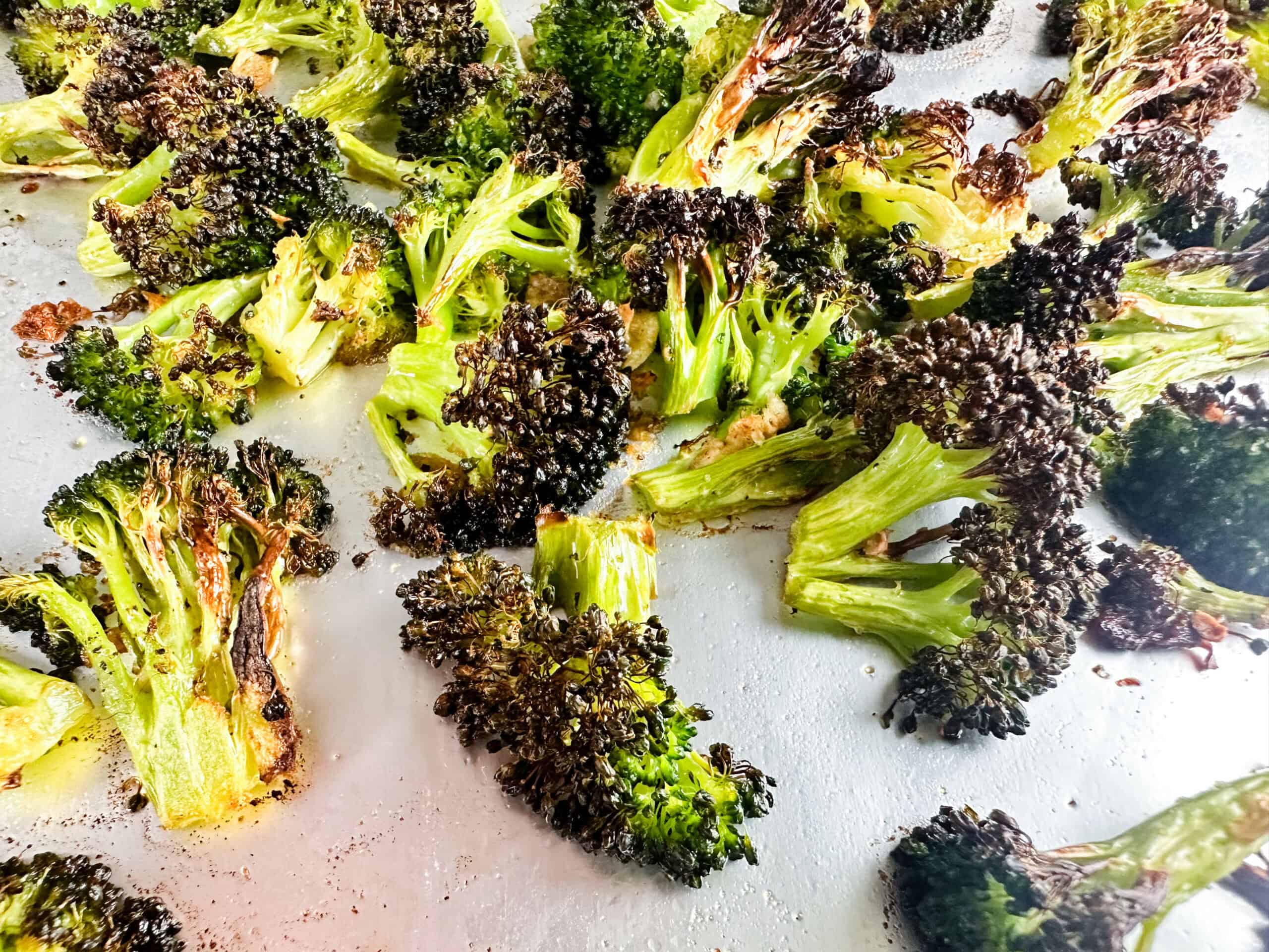 Garlic and roasted broccoli on a cookie sheet.