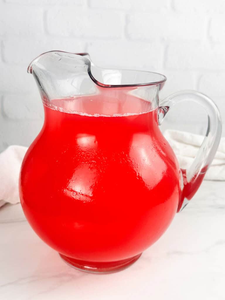 Pitcher of raspberry lemonade on a white background.