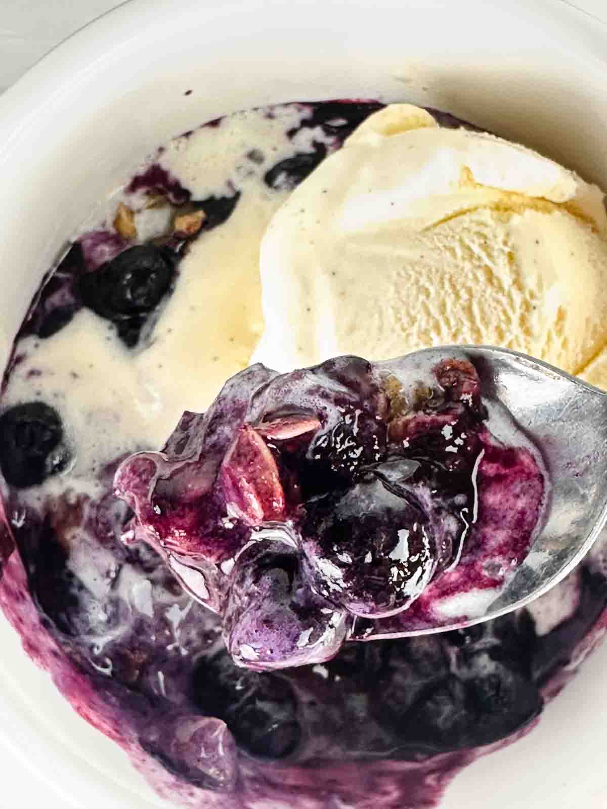 Spoon of blueberry crumble with ice cream and more below.