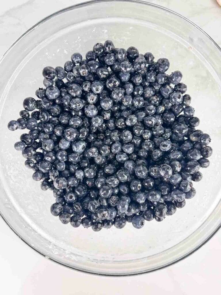 Blueberries mixed with cornstarch in a clear bowl.
