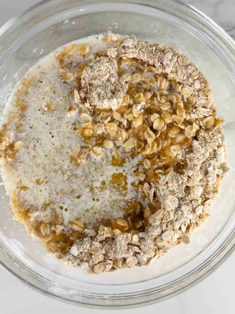 Melted butter, oats, and brown sugar in a clear mixing bowl.