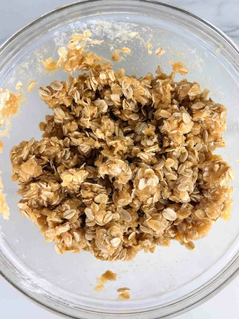 Oats mixed with butter and brown sugar in a clear bowl