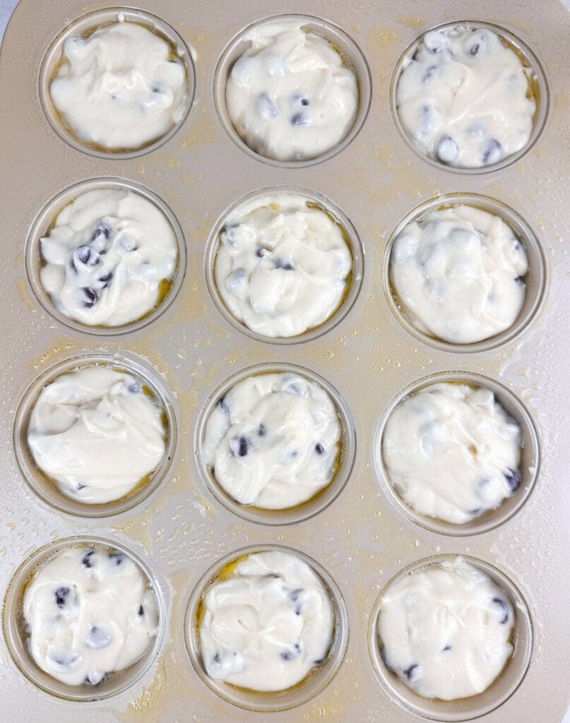 Filled muffin tin with chocolate chip muffin batter in each cup.