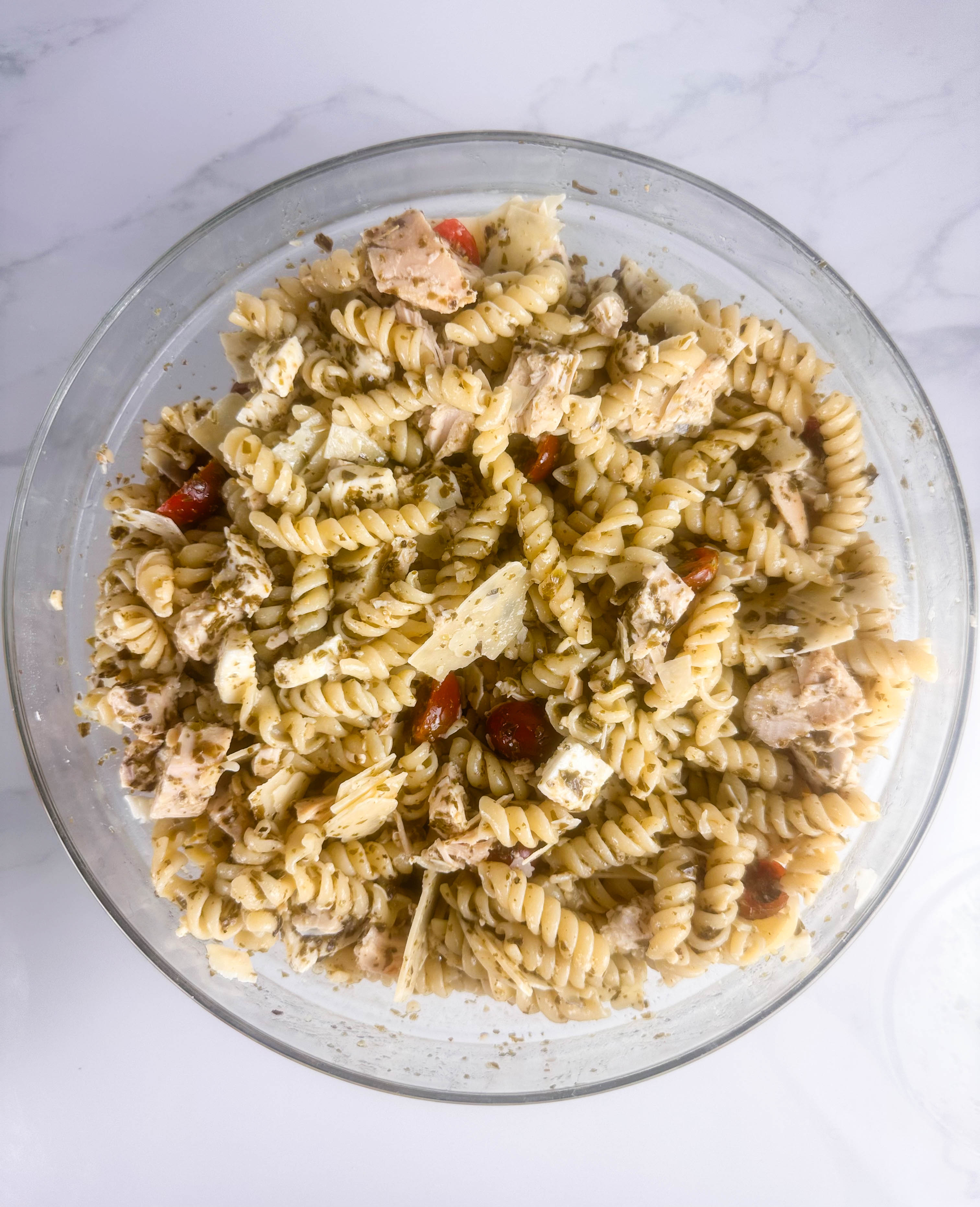 Chicken pesto pasta salad in a clear bowl.