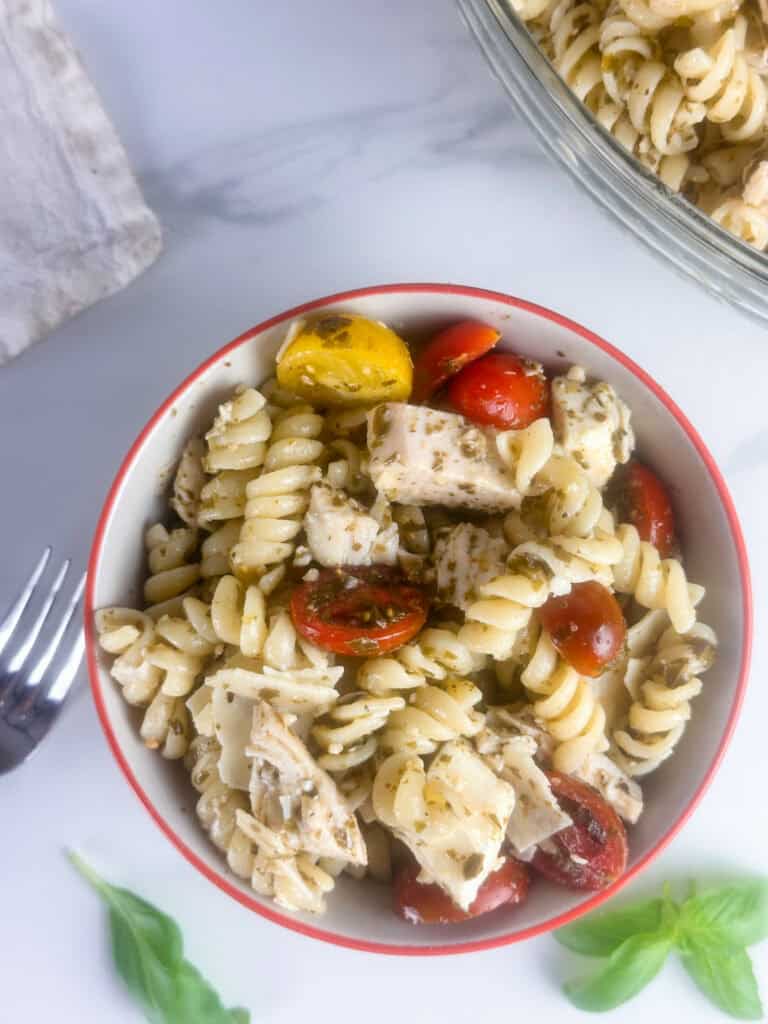 Ready to eat chicken pesto pasta salad in a small bowl.
