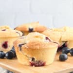 Fully baked buttermilk blueberry muffins on a wood cutting board.