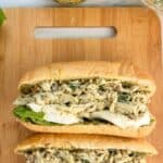 Image of two pesto chicken salad sandwiches on a wood cutting board. Text reads pesto chicken salad, seasonedsprinkles.com