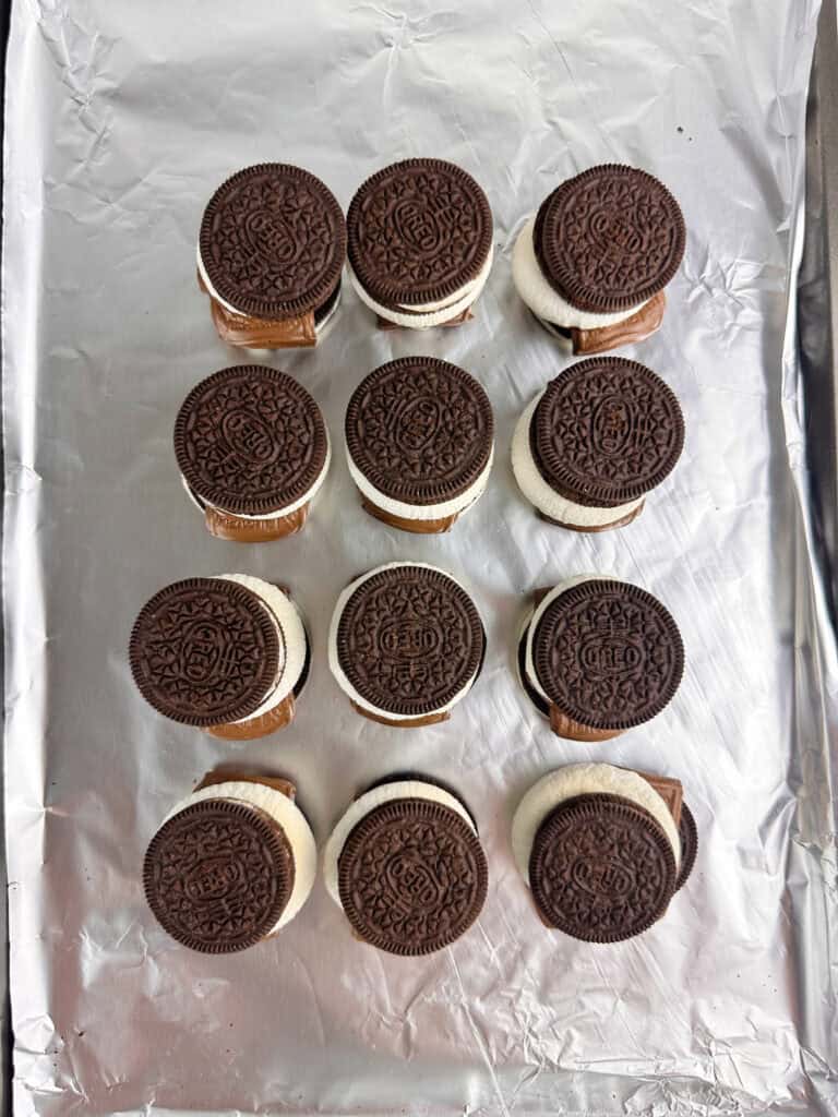Oreos set on top of baked marshmallows on a cookie sheet.