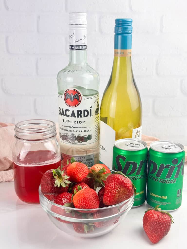 Ingredients for strawberry sangria: strawberries, strawberry simple syrup, rum, white wine, and Sprite.