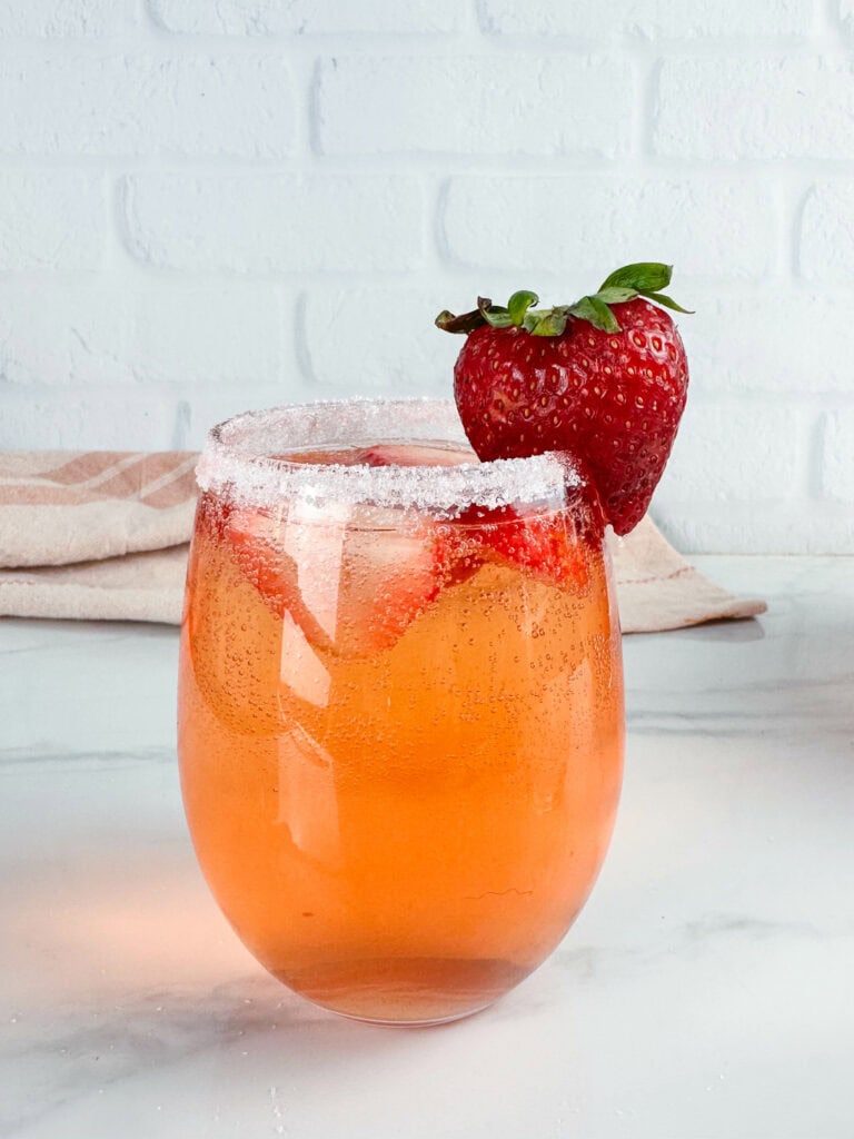Glass of strawberry sangria with frosted top and strawberries.