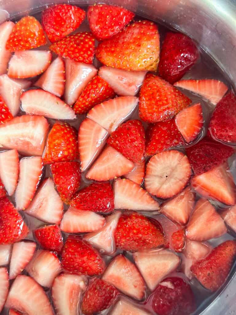 Sliced strawberries simmering in a pot of simple syrup