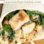Chicken caesar wrap ready to eat on a wood cutting board. Text reads: chicken caesar wrap, seasonedsprinkles.com
