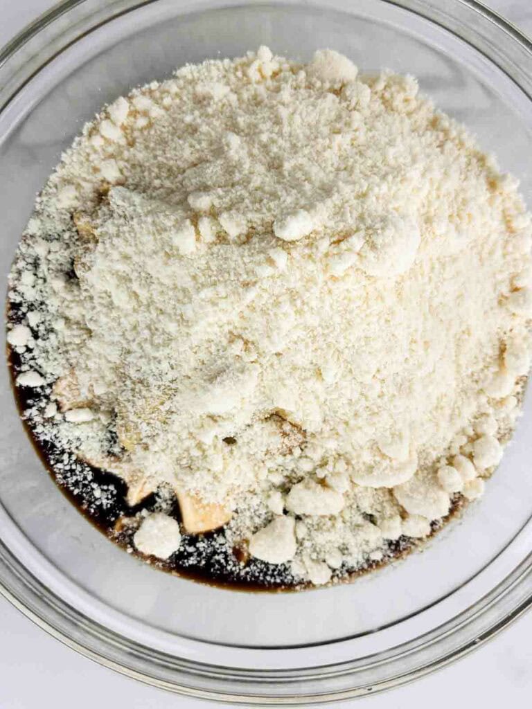 Ingredients of Caesar salad dressing without anchovies in a clear mixing bowl.