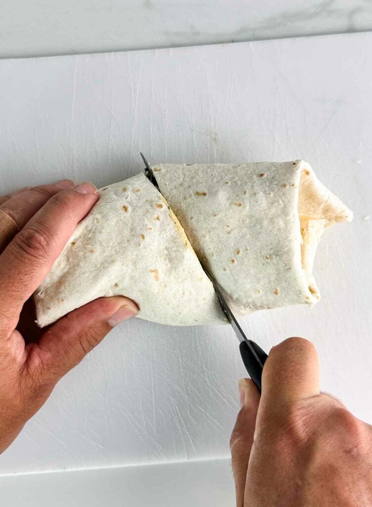 Cutting a chicken Caesar salad wrap in half.