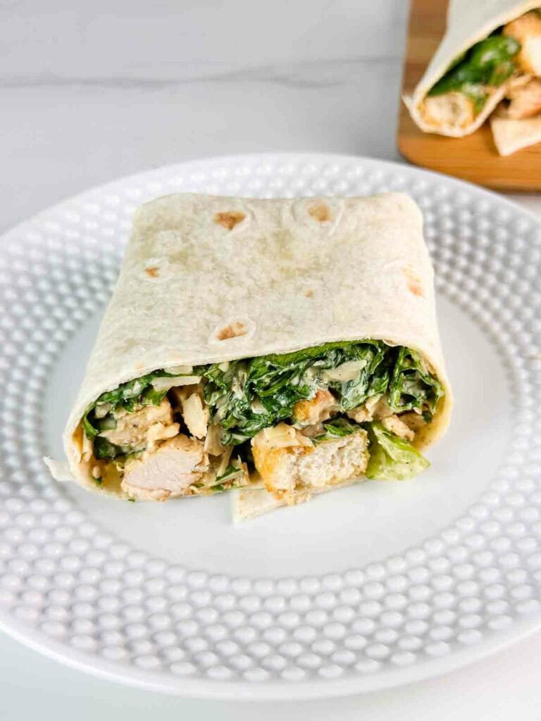 Chicken Caesar Salad Wrap cut in half on a white plate.