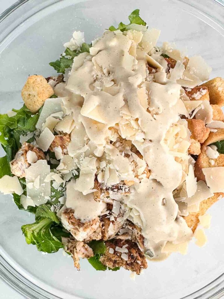 All the ingredients for a chicken caesar salad in a bowl.