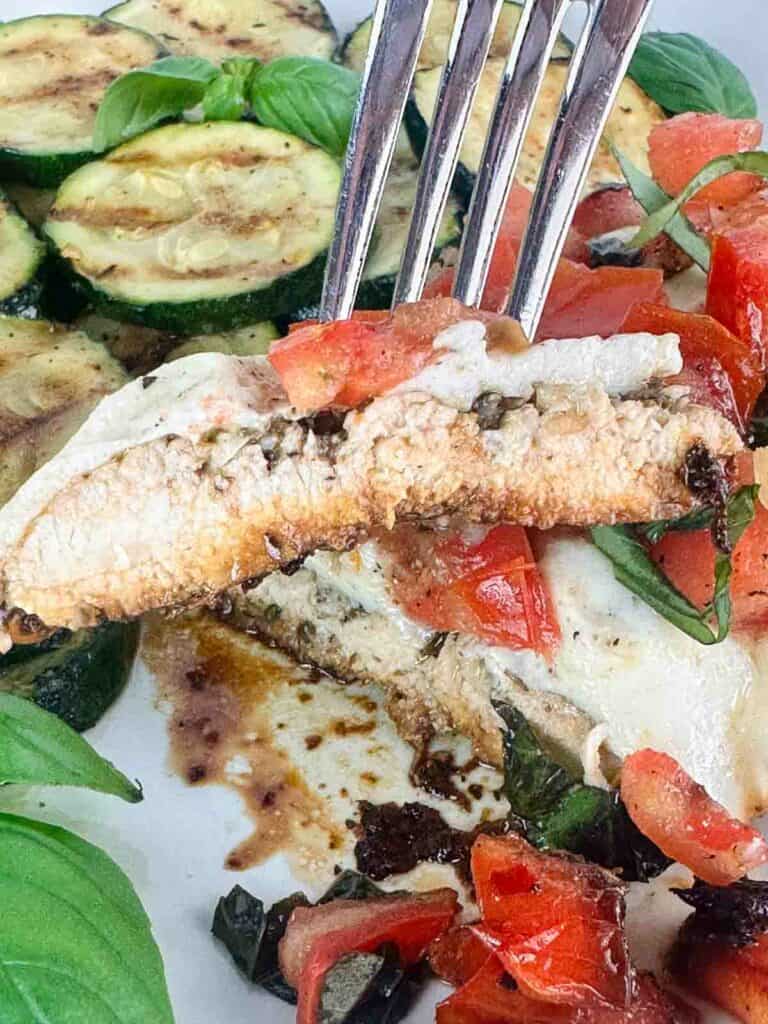 Slice of bruschetta chicken held with a fork.