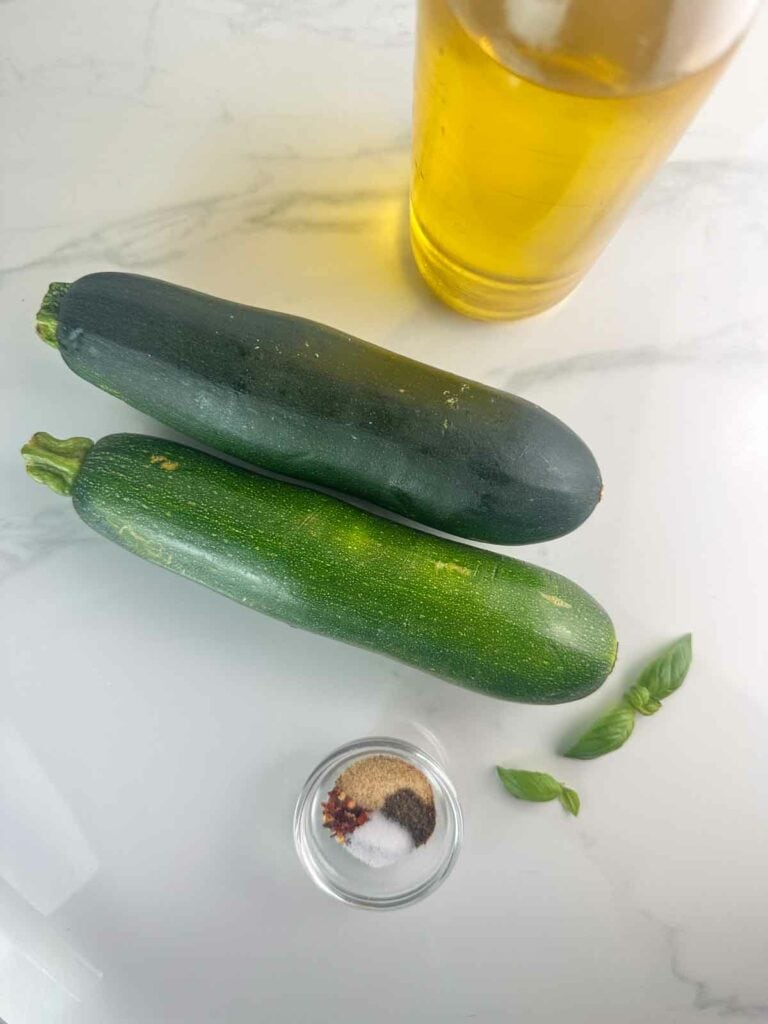 Ingredients for grilled zucchini: olive oil, zucchini, garlic powder, salt, pepper, and red pepper flakes (optional).
