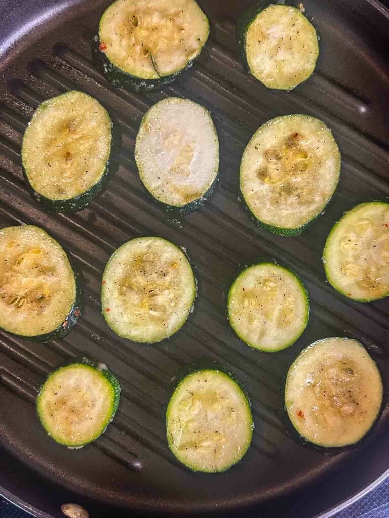 Grilling zucchini rounds in a grill pan.