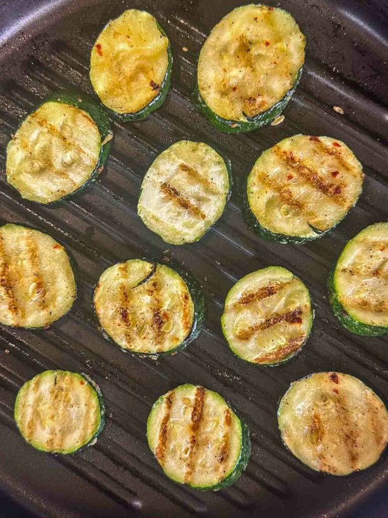 Zucchini rounds with grill marks in a grill pan.