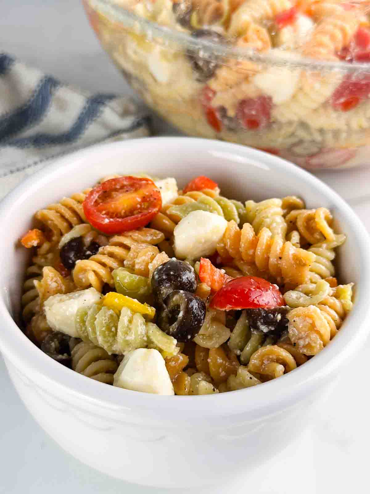 Serving of pasta salad with the serving bowl.