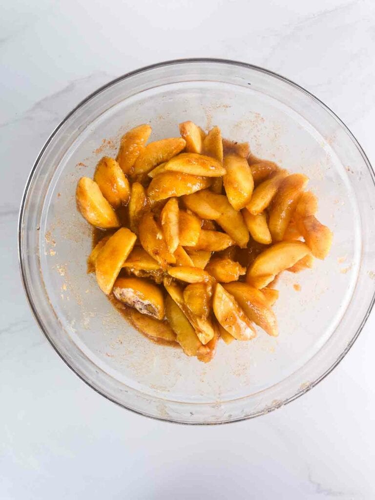 Peaches mixed with brown sugar and other ingredients for cobbler.