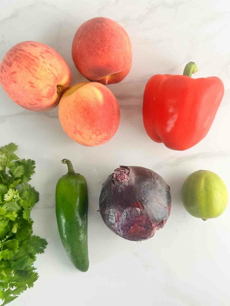 Ingredients for peach salsa: peaches, bell pepper, cilantro, jalapeno, red onion, and lime juice.