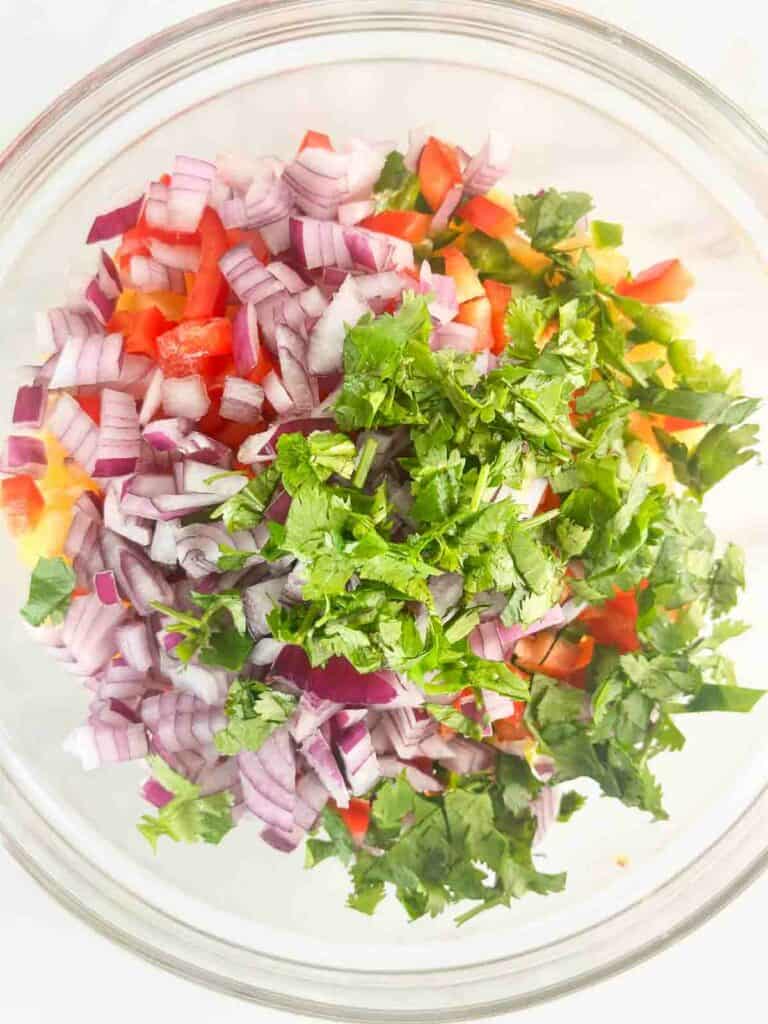 Cilantro added to a bowl for peach salsa ingredients.