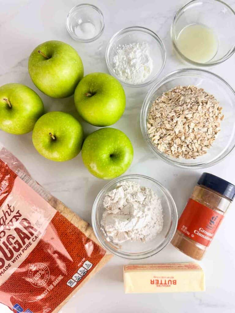 Ingredients for apple crumble recipe: salt, corn starch, lemon juice, apples, old fashioned oats, brown sugar, flour, cinnamon, and butter.
