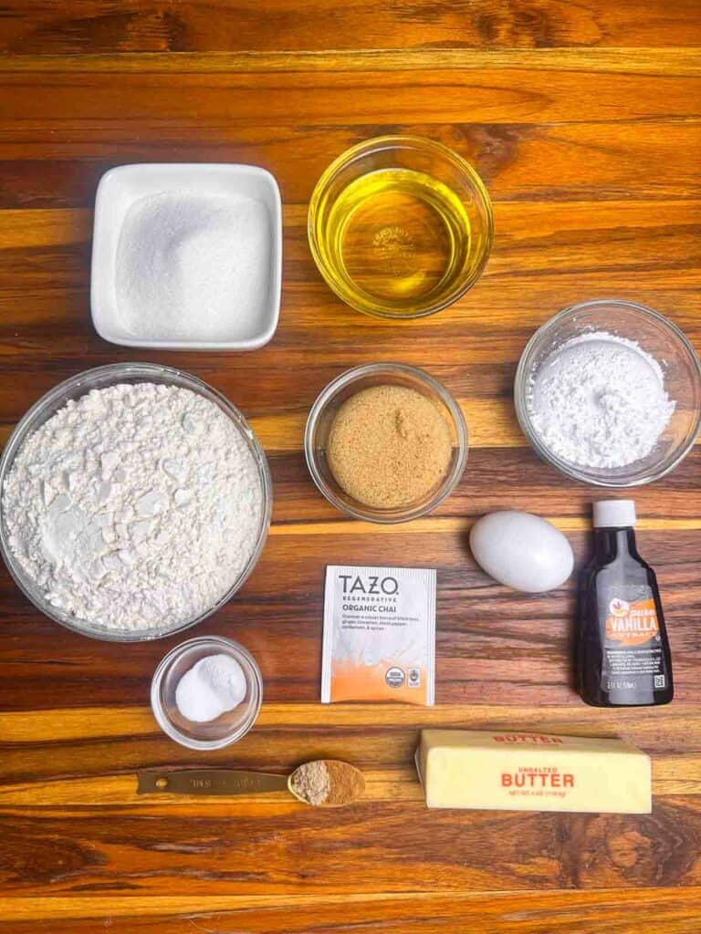 Ingredients for chai cookies: grandulated sugar, canola oil, flour, brown sugar, powdered sugar, salt, baking soda, chai tea bag, egg, vanilla, cardamom, cinnamon, and butter.
