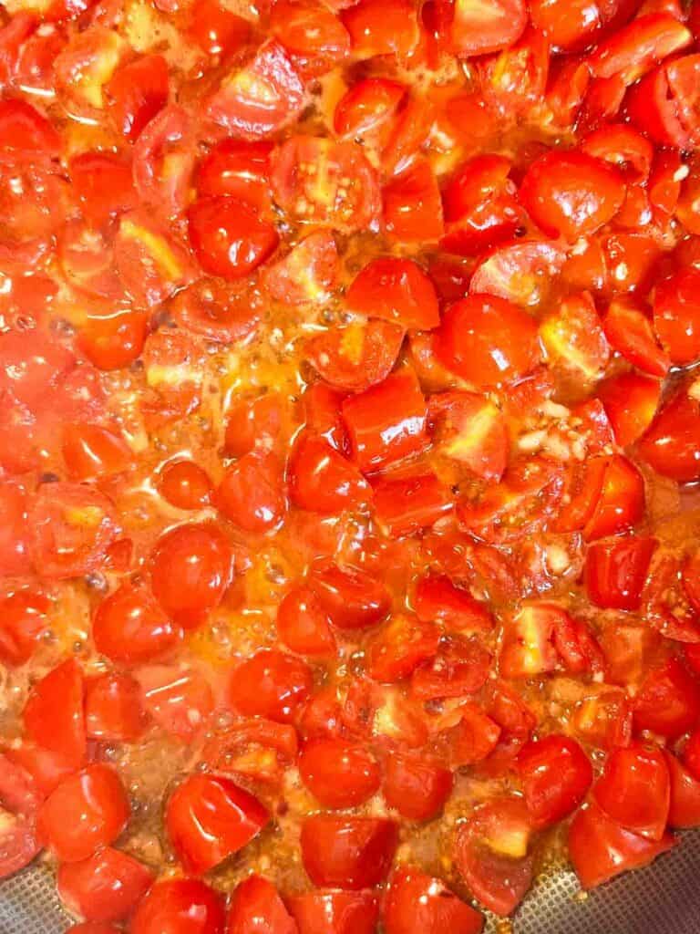 Tomatoes sauteing in a skillet.