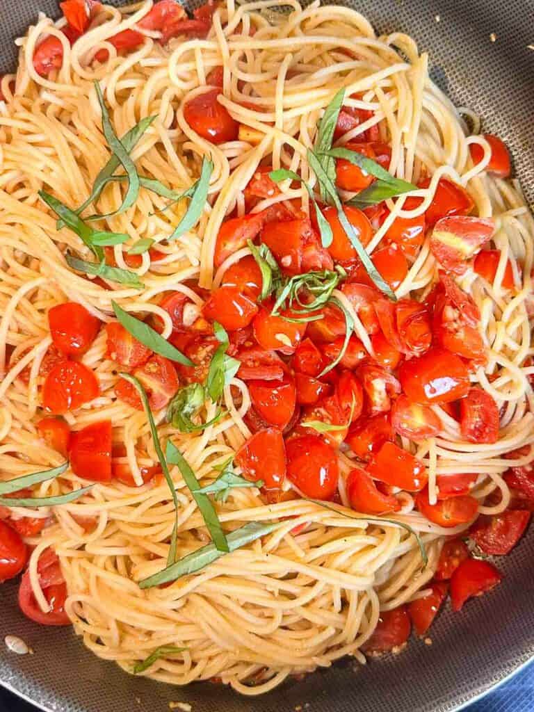 Cherry tomato pasta with basil and parmesan cheese in the skillet.