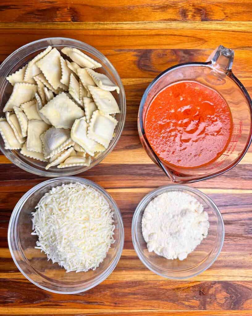 Ingredients for ravioli lasagna: frozen ravioli, tomato sauce, mozzarella cheese, and parmesan cheese.