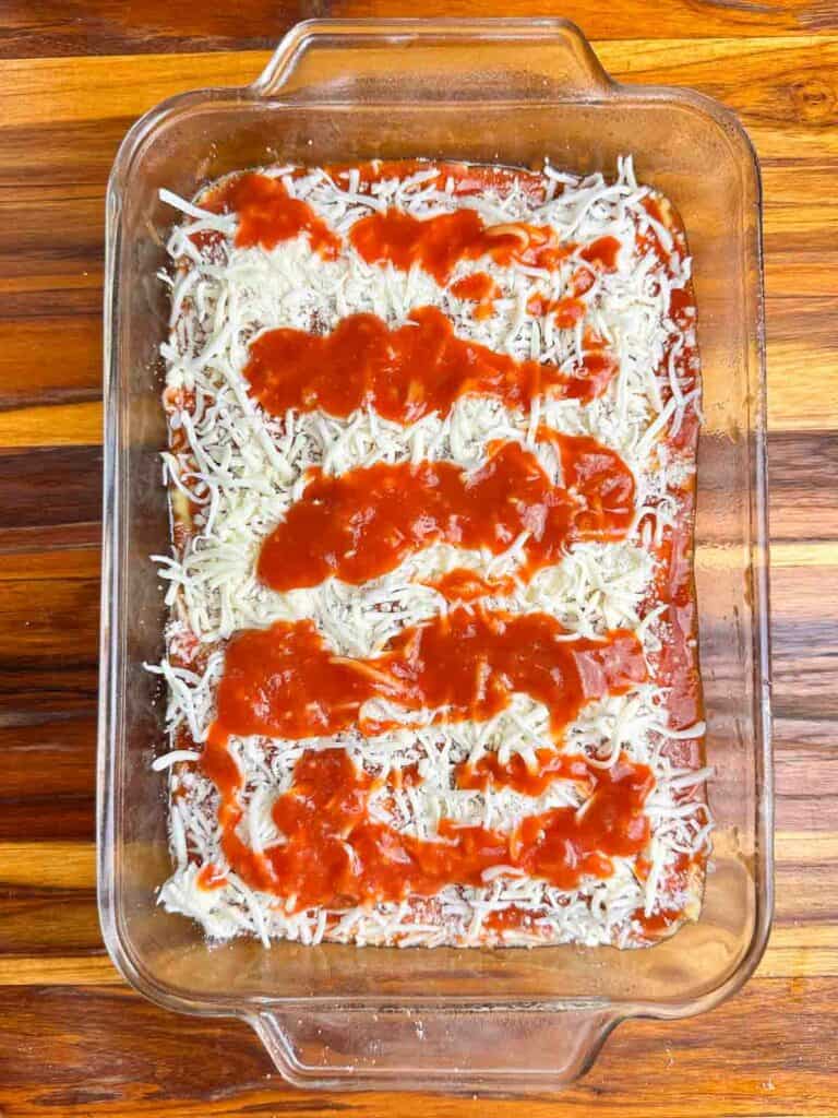 Cheese and sauce in a clear baking dish.