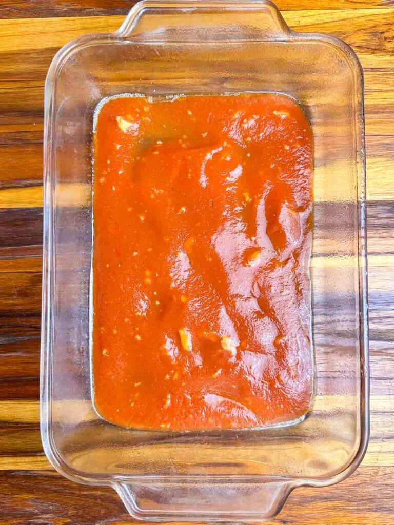 Sauce on the bottom of a clear baking dish.