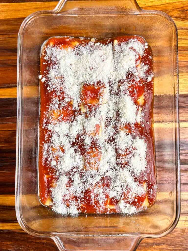 Parmesan cheese sprinkled on top of of red sauce and ravioli.
