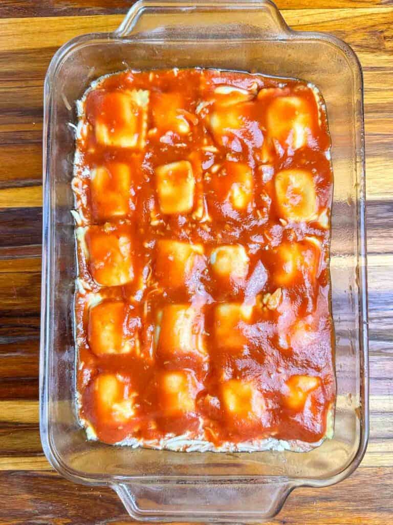 Ravioli covered with red sauce in a baking dish.