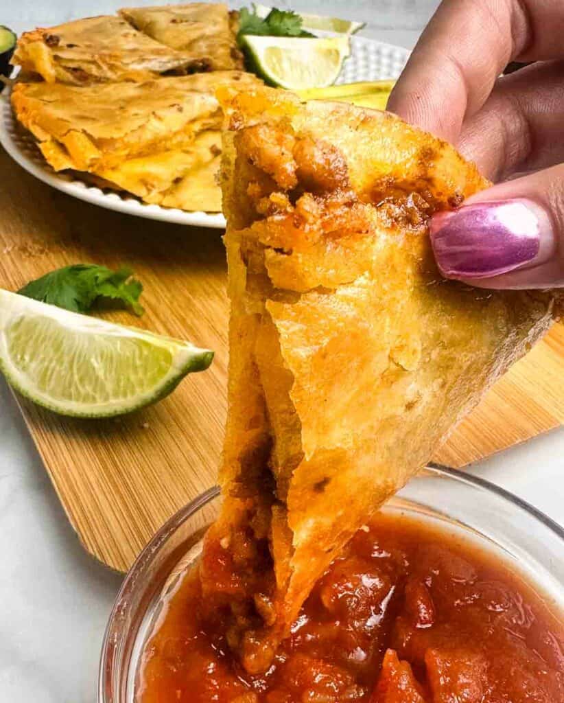 Dipping chicken quesadilla wedge into salsa.
