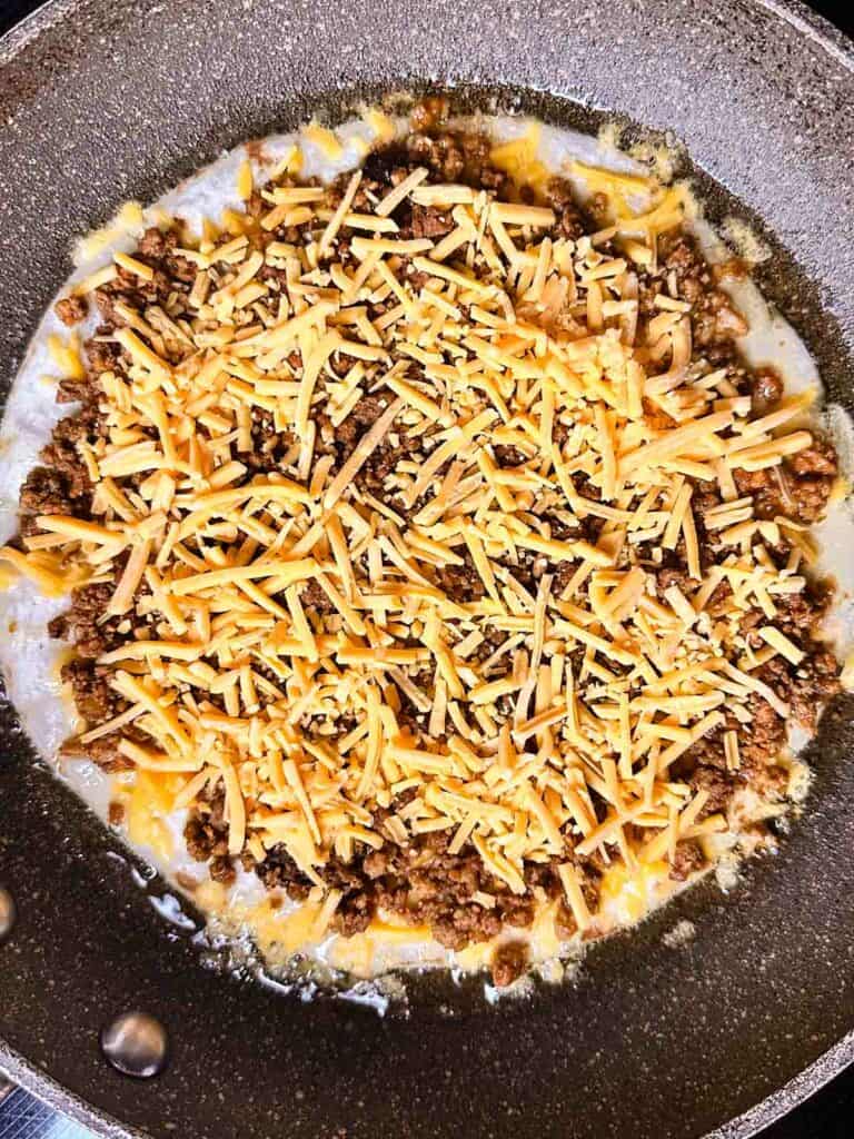 Topping chicken quesadilla with cheese.