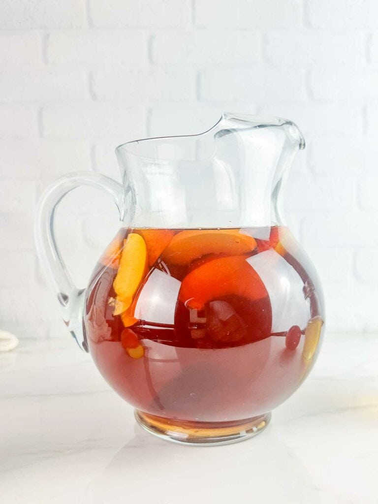 Sliced peaches added to pitcher of black tea.