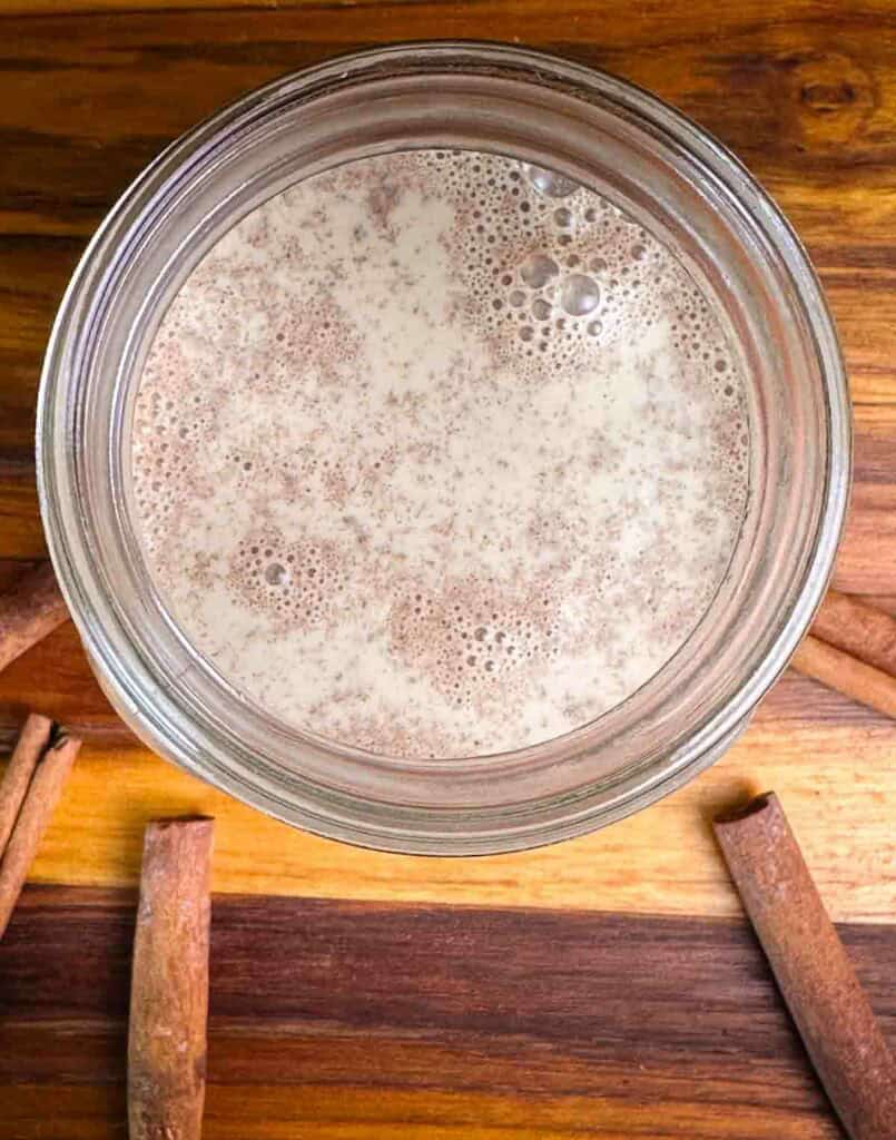 Mason jar of pumpkin spice coffee creamer in front of a dark background.