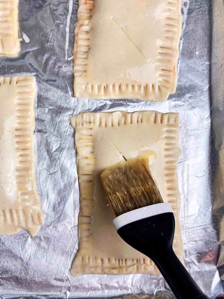 Brush a the homemade strawberry pop tarts with egg wash using a pastry brush