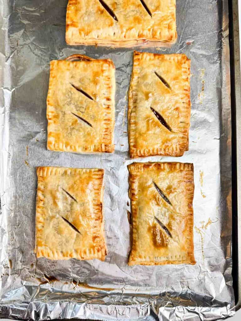 5 homemade strawberry pop tarts on a baking sheet fresh out of the oven
