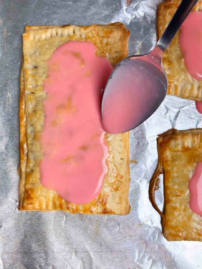 Spooning pink icing on a homemade strawberry pop tart