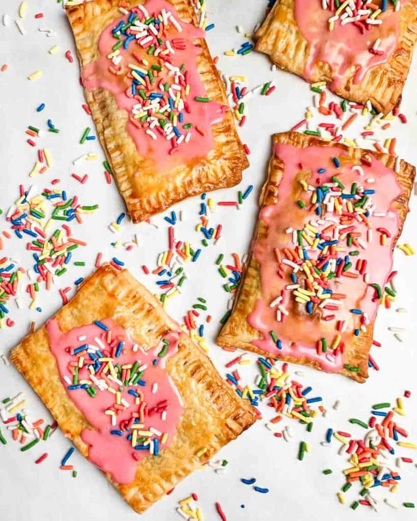 Hmemade strawberry pop tarts with pink icing and rainbow sprinkles