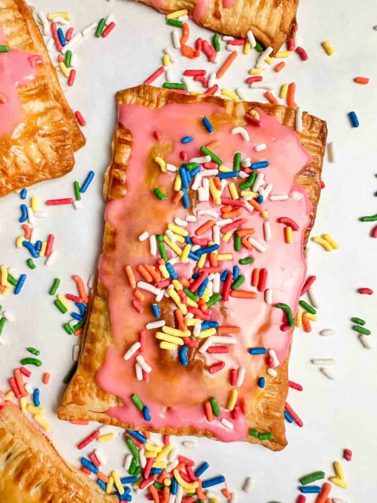 Homemade strawberry pop tarts with pink icing and rainbow sprinkles