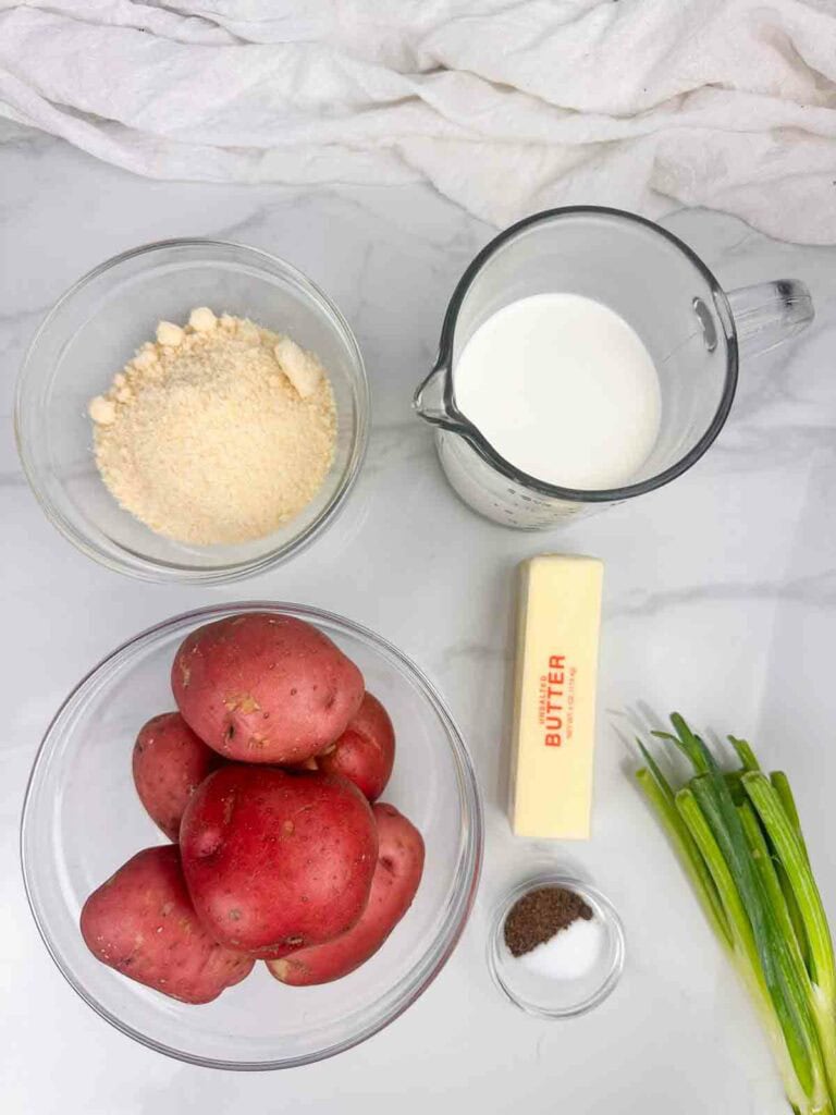 Ingredients for mashed potatoes with red skin: parmesan, cream, red skinned potatoes, butter, salt, and pepper.