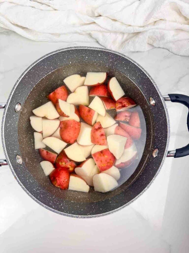 Pot of water with cubed red skinned potatoes.