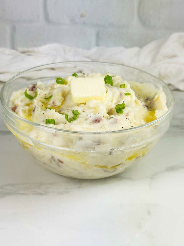 Mashed potatoes with red skinned with green onions and pad of butter on top.