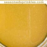 Peach simple syrup in a mason jar. Text reads: peach simple syrup recipe, seasonedsprinkles.com